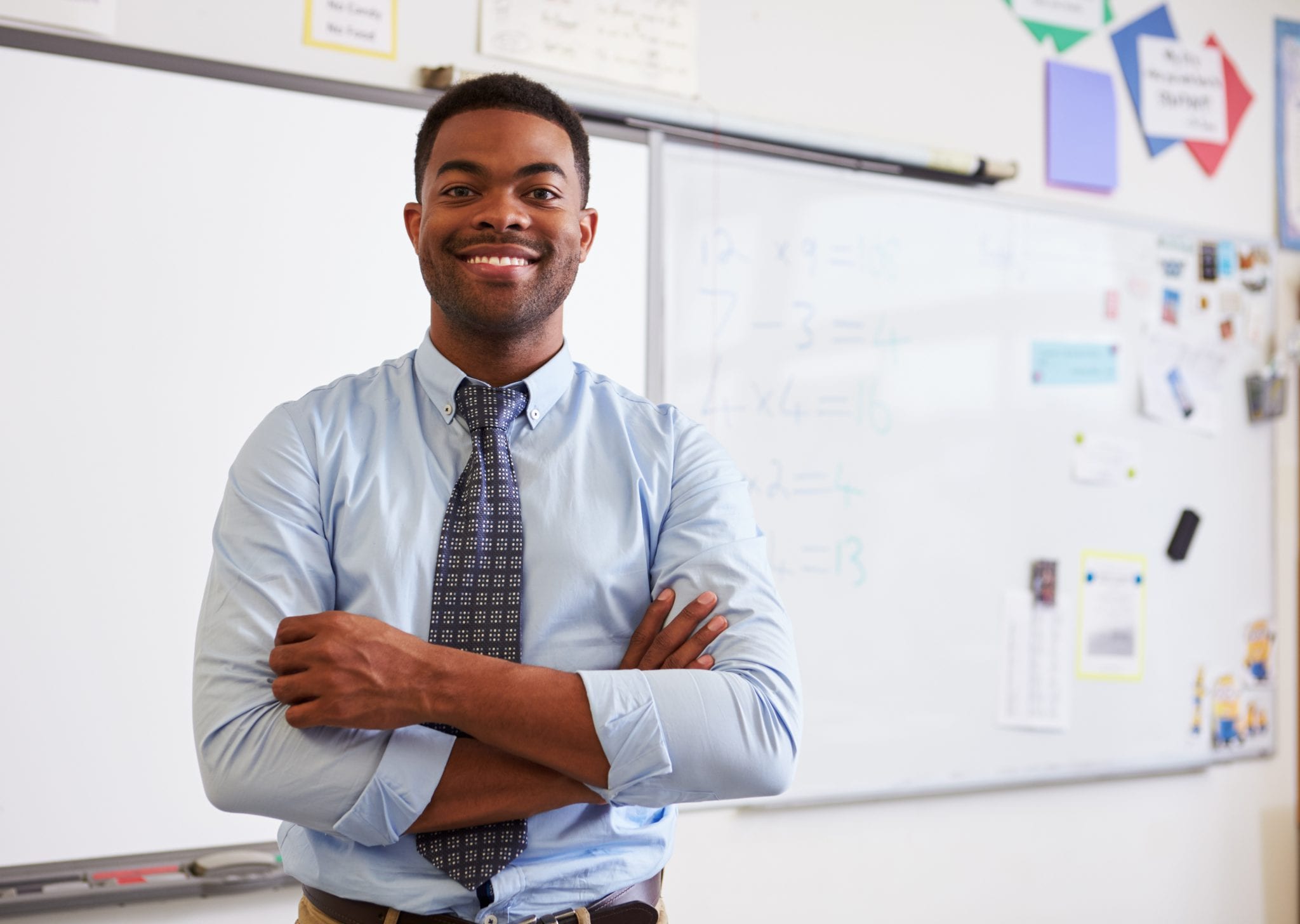 teacher smiling in front of classroom whiteboard